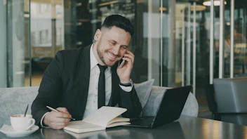 Man in suit talking on phone while writing