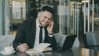 Man in suit talking on phone while writing
