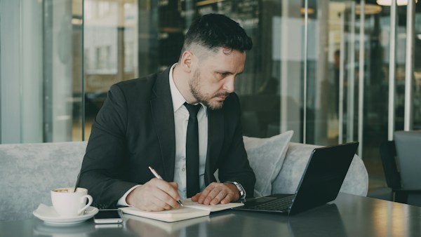 Man in suit writing in notebook