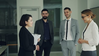 Four professionals in suits discussing in an office.