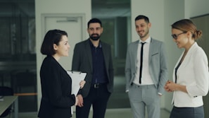 Four professionals in suits discussing in an office.