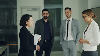 Four professionals in suits discussing in an office.