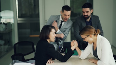 Two women arm wrestling at a table