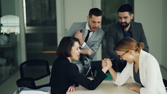 Two women arm wrestling at a table