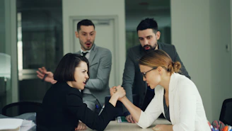 Two women arm wrestling with men watching