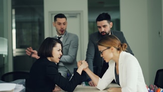Two women arm wrestling with men watching