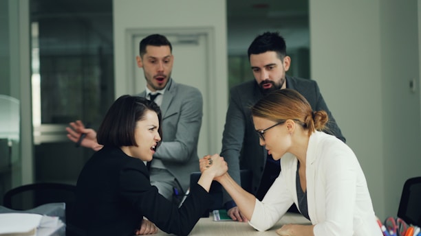 Two women arm wrestling with men watching