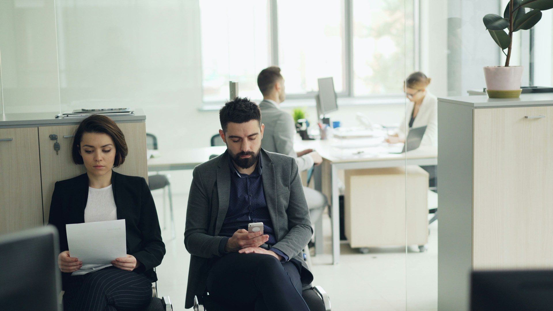 Two people waiting in an office lobby