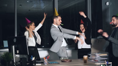 People in party hats dancing in an office at-work celebration.