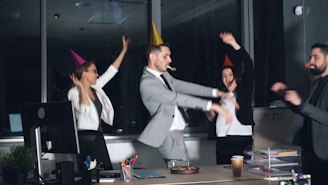 People in party hats dancing in an office at-work celebration.