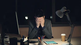 Man in suit sits at desk, head in hands. echofrei spricht über existenzängste von unternehmern