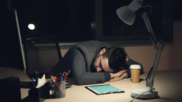 Man sleeping at desk with coffee and tablet.