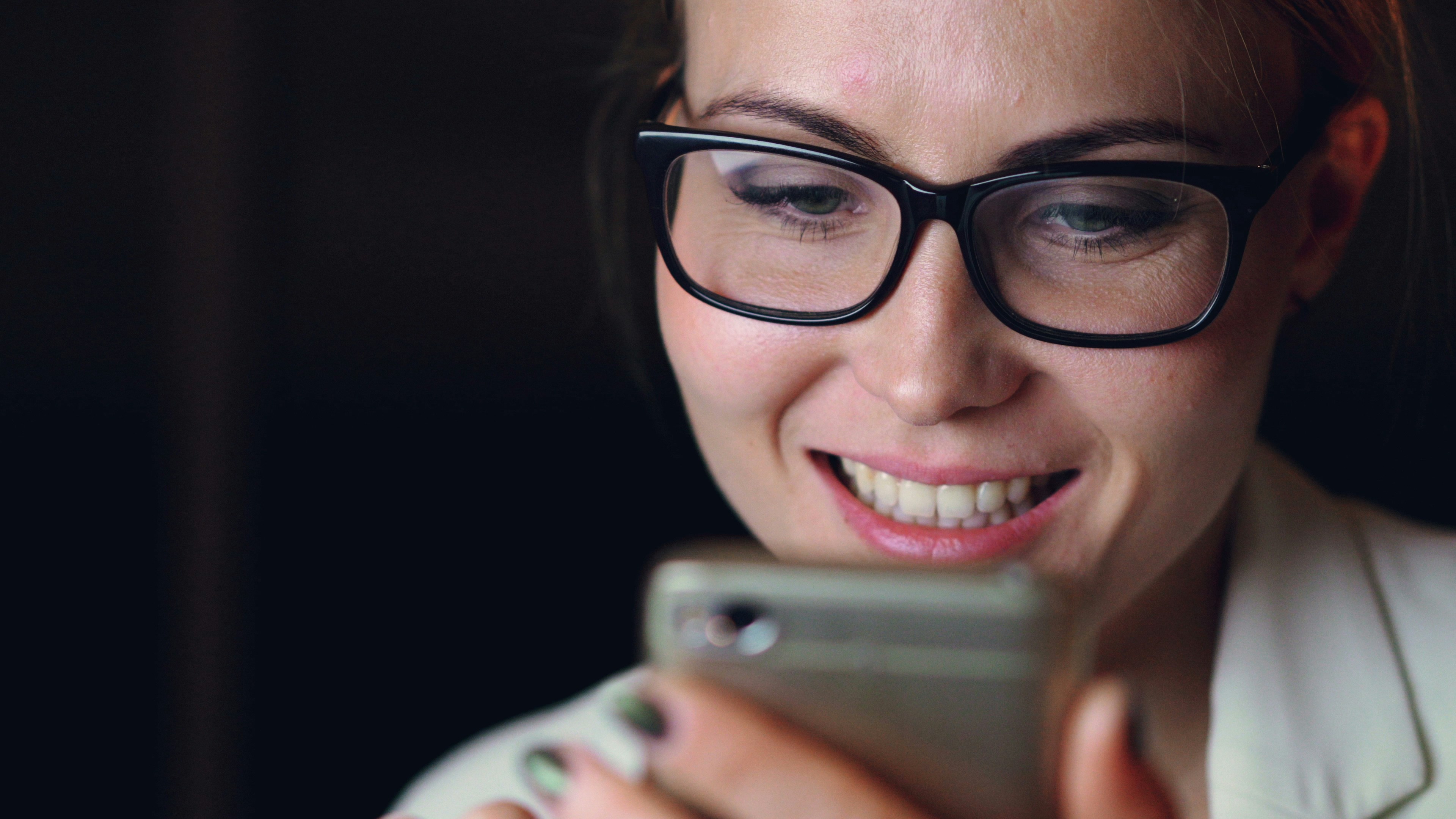 person smiling while looking at a phone in low light