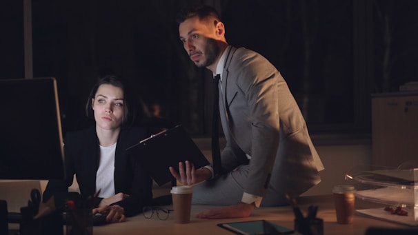 Two colleagues working late in a dimly lit office.