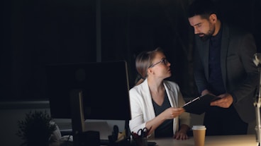 Two colleagues working late in a dimly lit office.