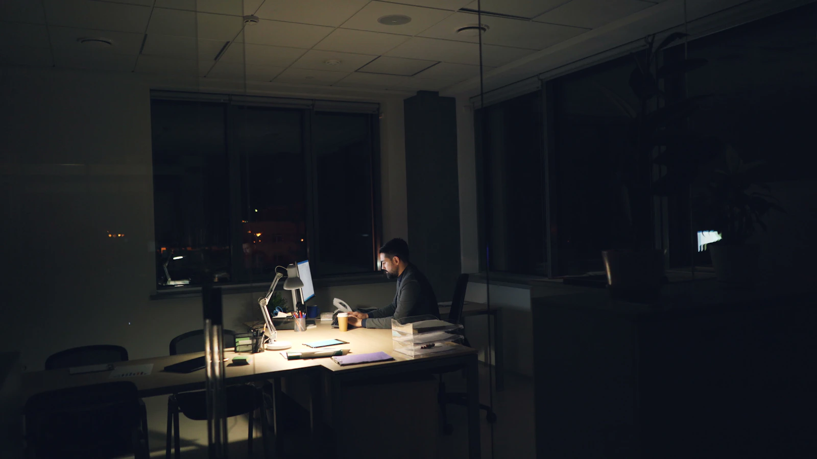 Escritorio de oficina iluminado tenuemente de noche, representando la atención fuera de horario
