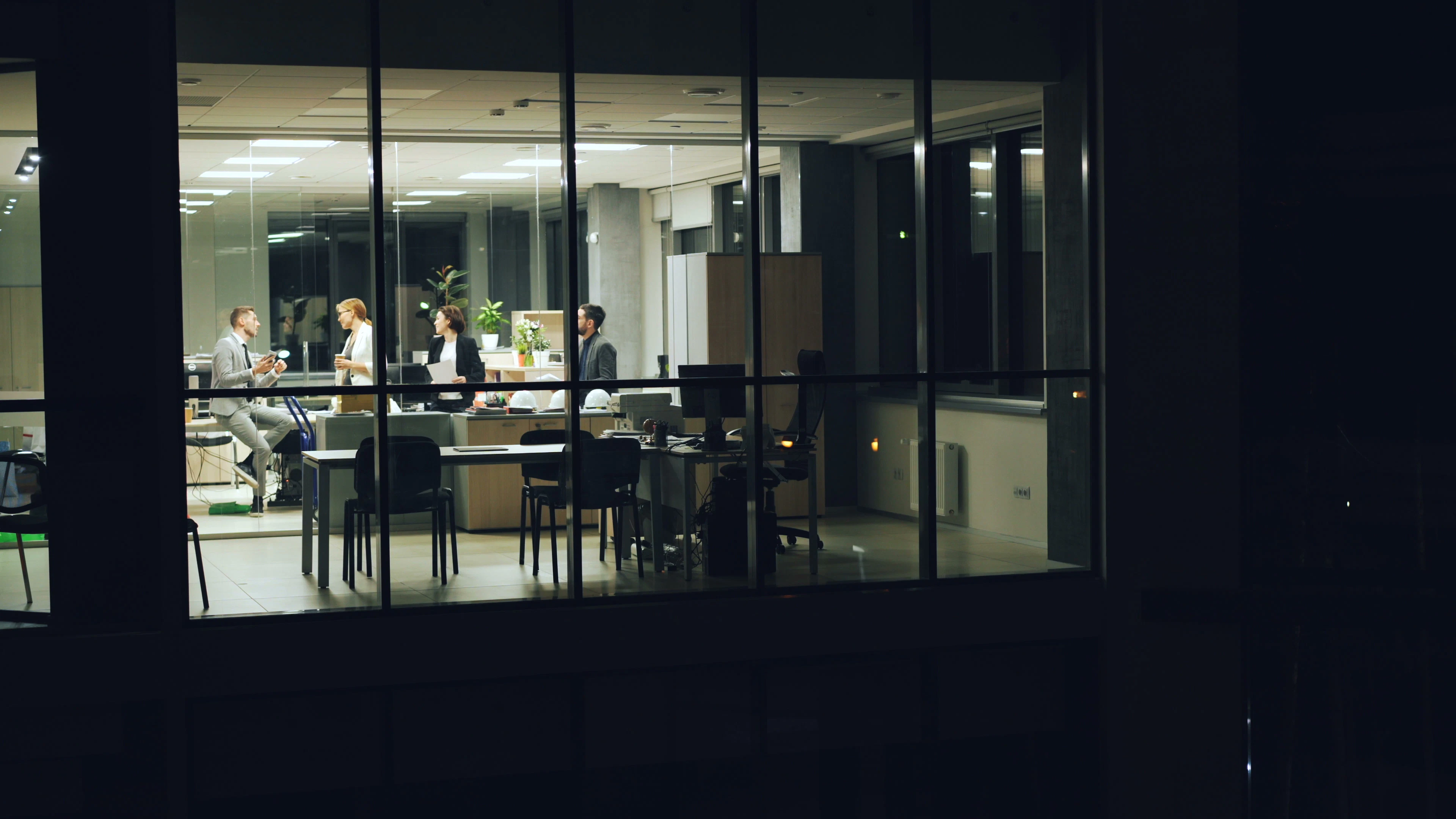 A team working together in a glass-walled office in the evening