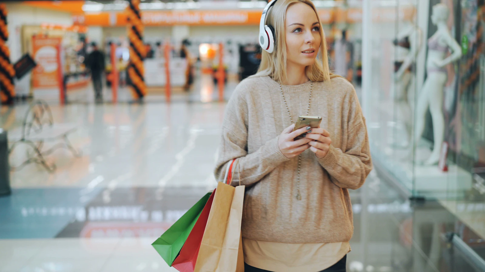 A woman with shopping bags checking her phone in a shopping mall