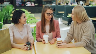 Three women over 40 sharing stories over coffee.
