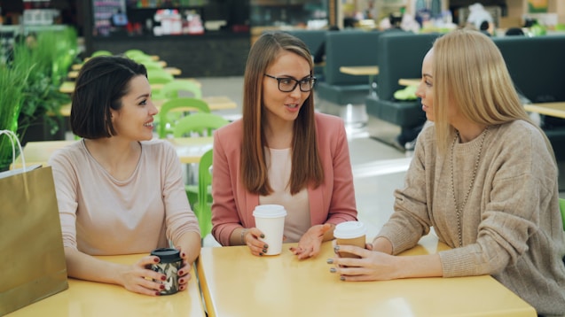 Three women over 40 sharing stories over coffee.