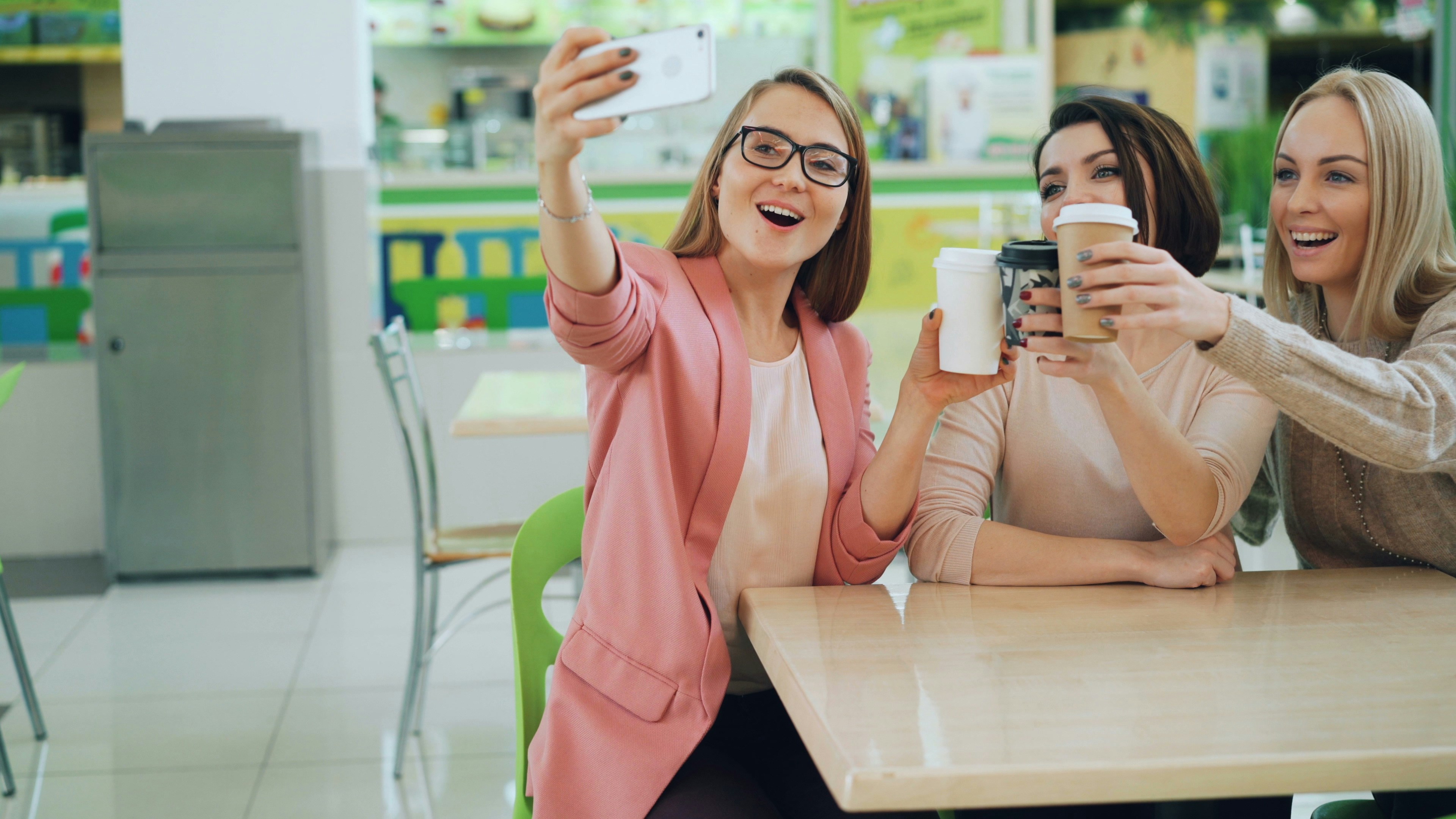 Three women taking a selfie and toasting with drinks