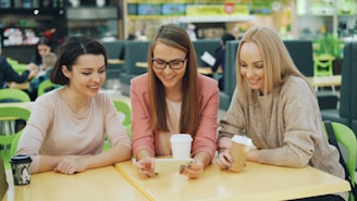 Three friends looking at a phone at a table.