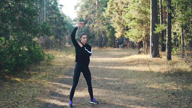 A woman stretching on a forest path in morning light