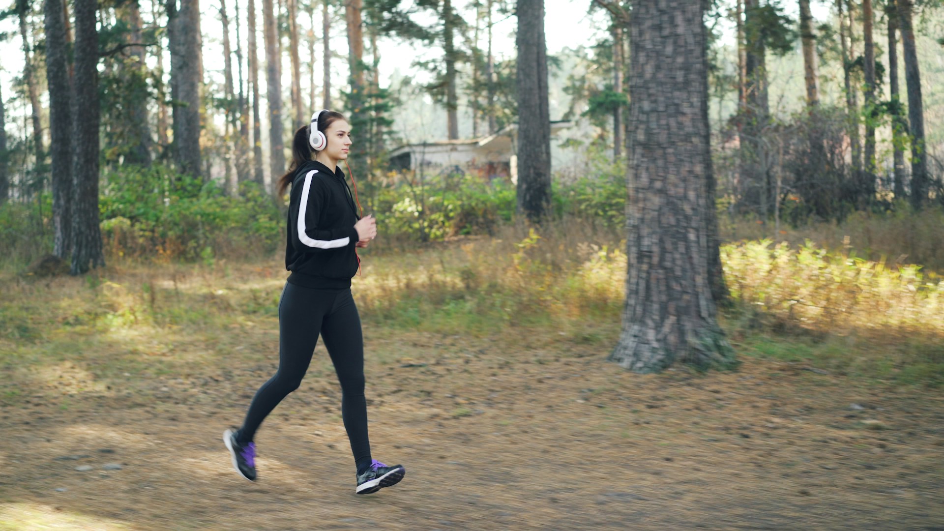 Woman jogging in a forest wearing headphones
