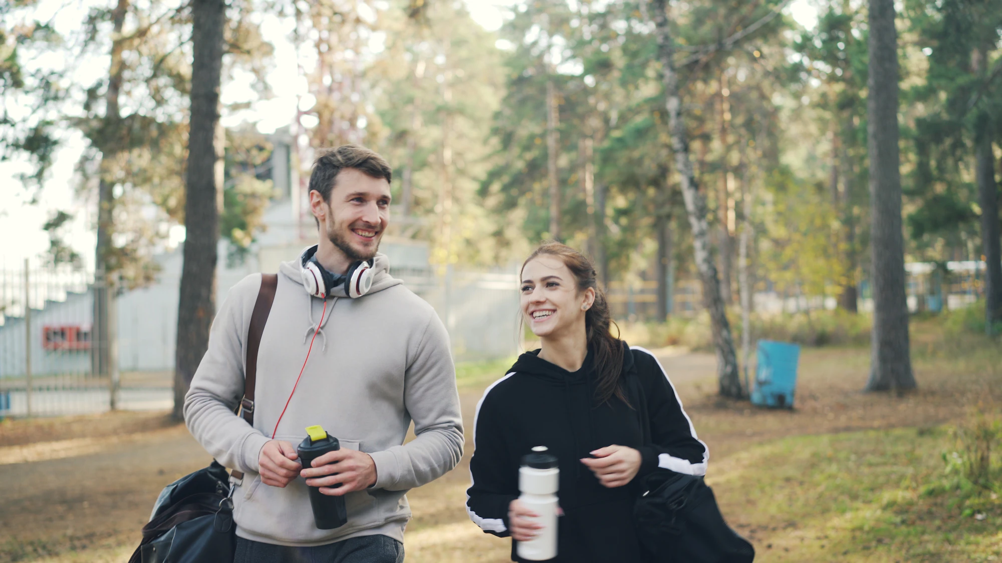 Couple walking outdoors with gym bags and water bottles