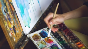 Artist painting with watercolors on canvas