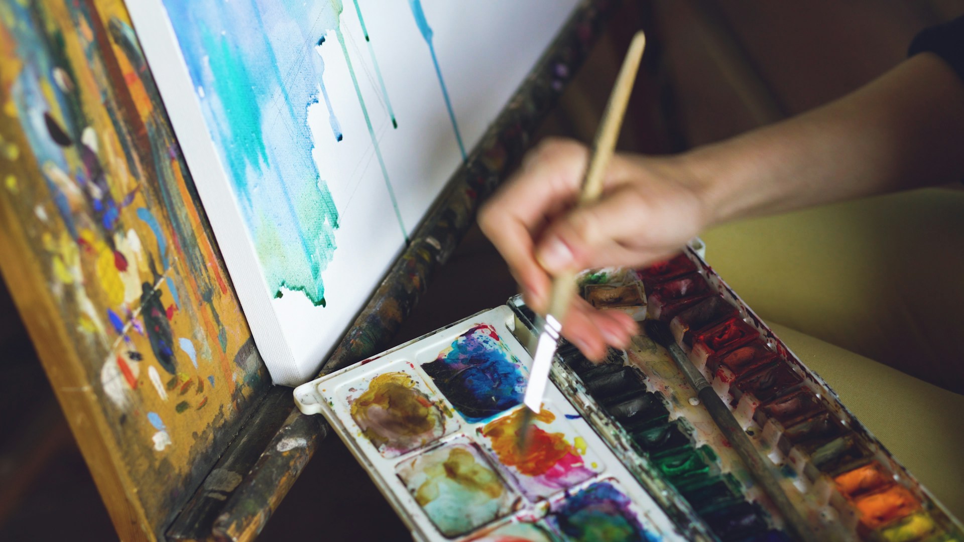 Artist painting with watercolors on canvas