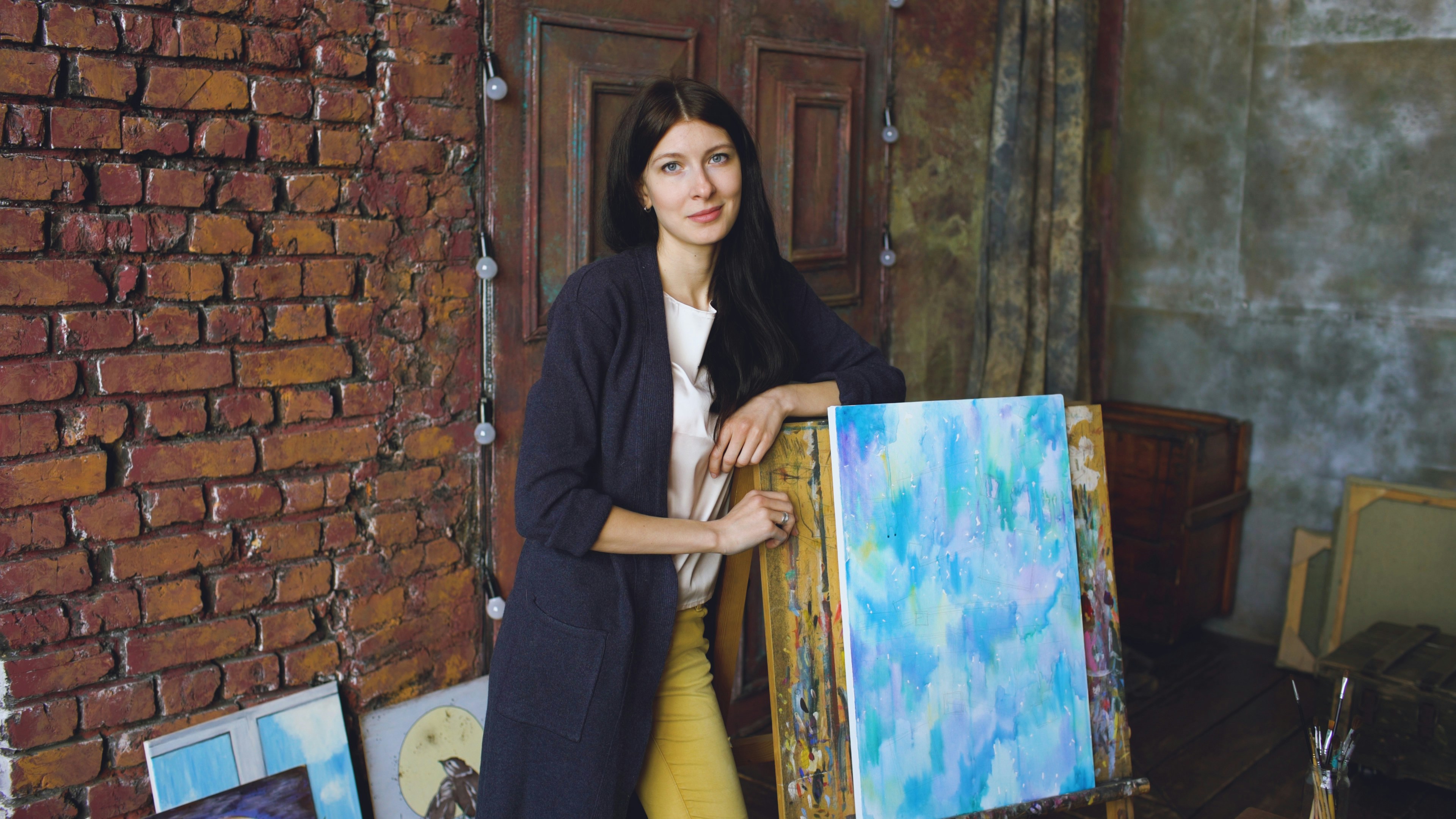 Artist with abstract paintings in studio
