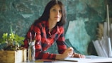 Woman in red plaid shirt drawing at desk