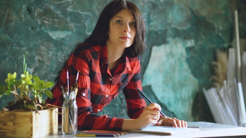 Woman in red plaid shirt drawing at desk