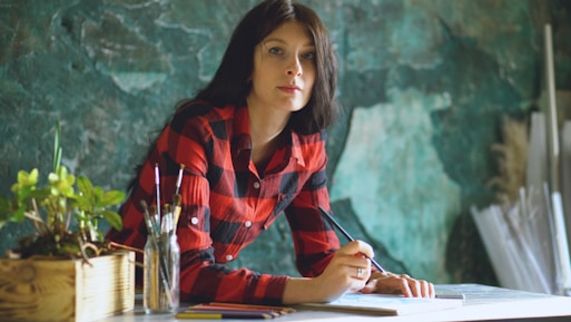 Woman in red plaid shirt drawing at desk