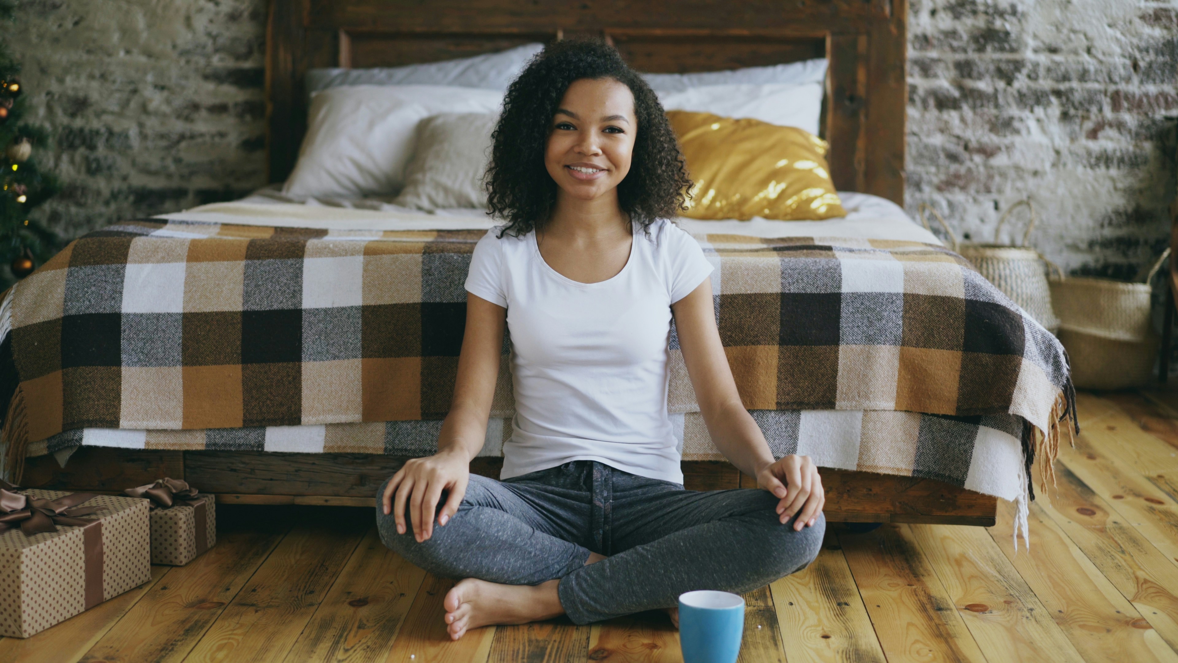 Young woman sitting cross-legged with a cup.