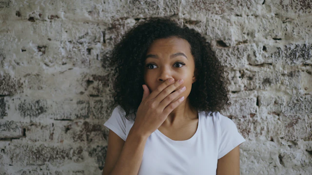 Woman with hand over mouth looking surprised