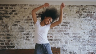 Young woman with afro dancing joyfully in room