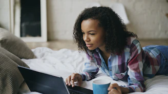 Young woman working on laptop in bed