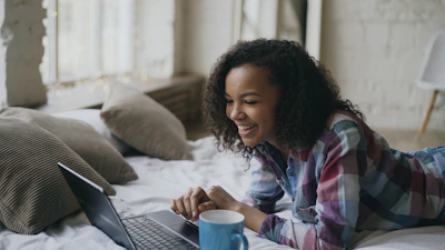 Young woman laughing while looking at laptop on laptop