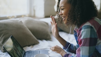 A young woman waves during a video call on laptop.