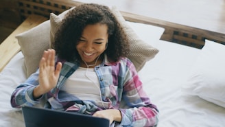 Young woman waving hello while video chatting on laptop.