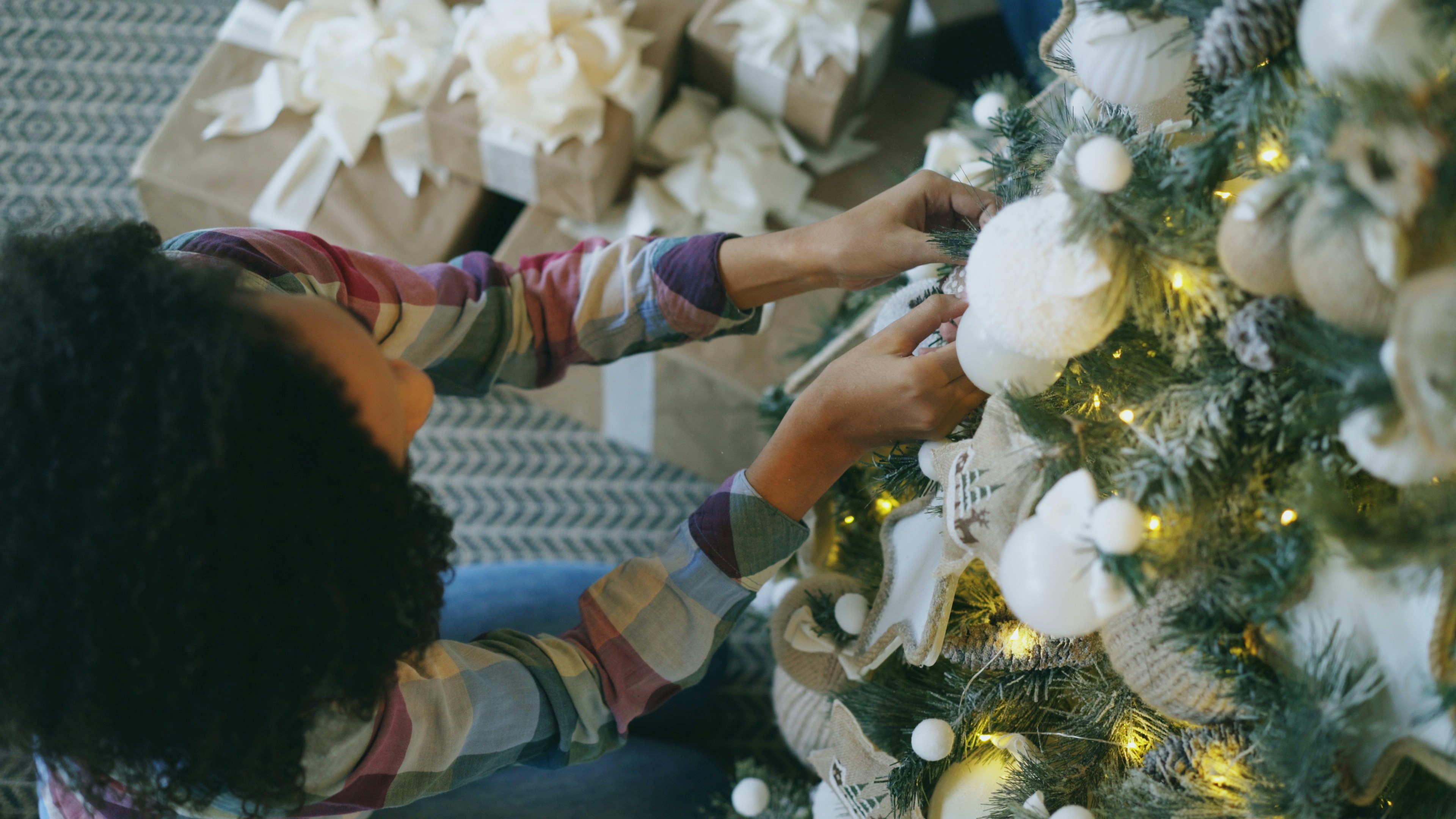 A person decorating a christmas tree with ornaments