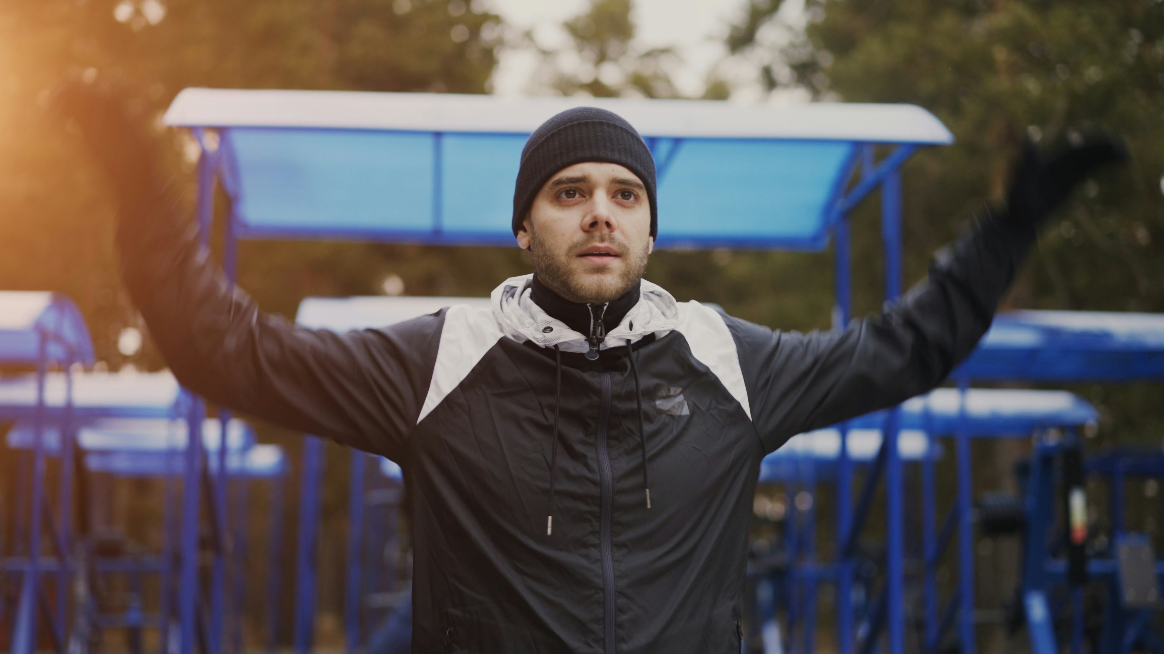 Man in beanie and jacket with arms raised