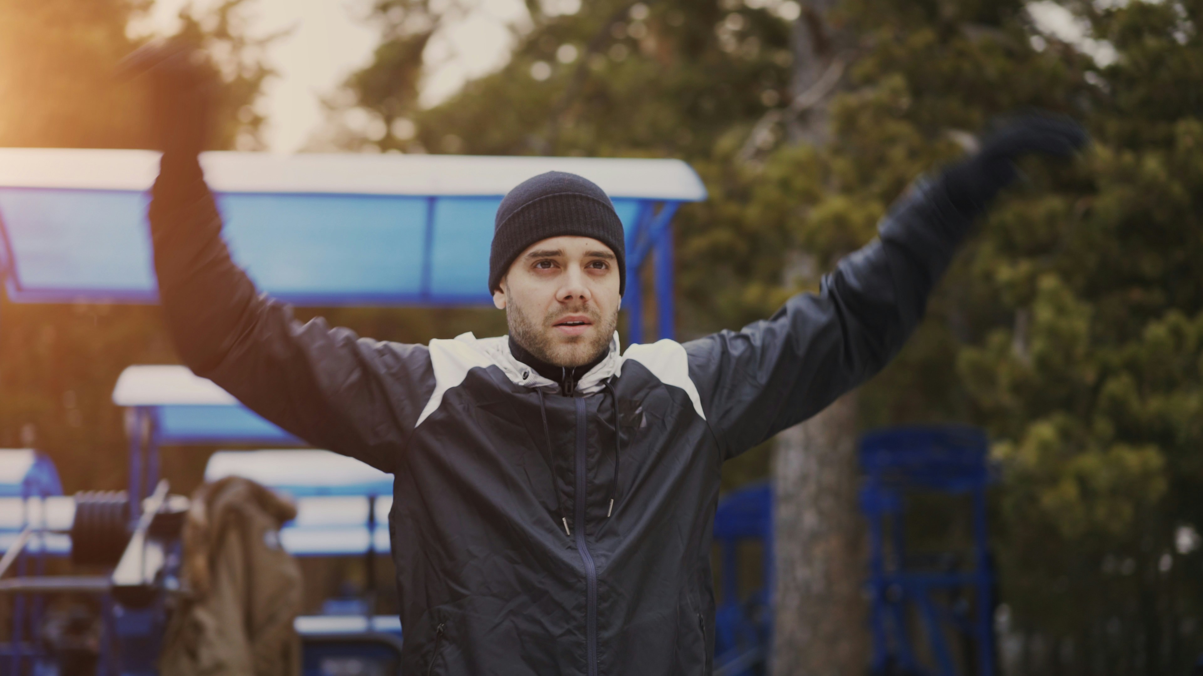 Man in beanie and jacket stretching outdoors