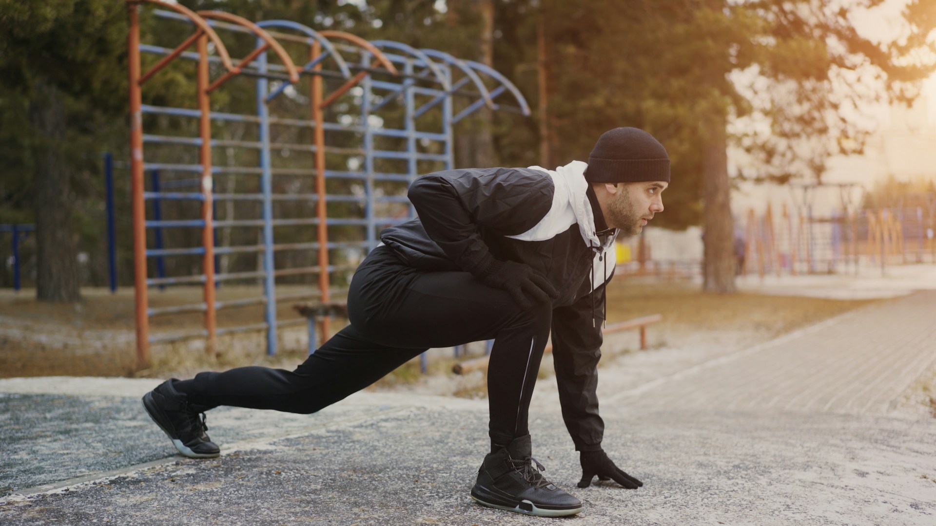 Man stretching outdoors near playground equipment.