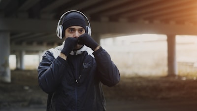 Man wearing headphones boxing outdoors under bridge