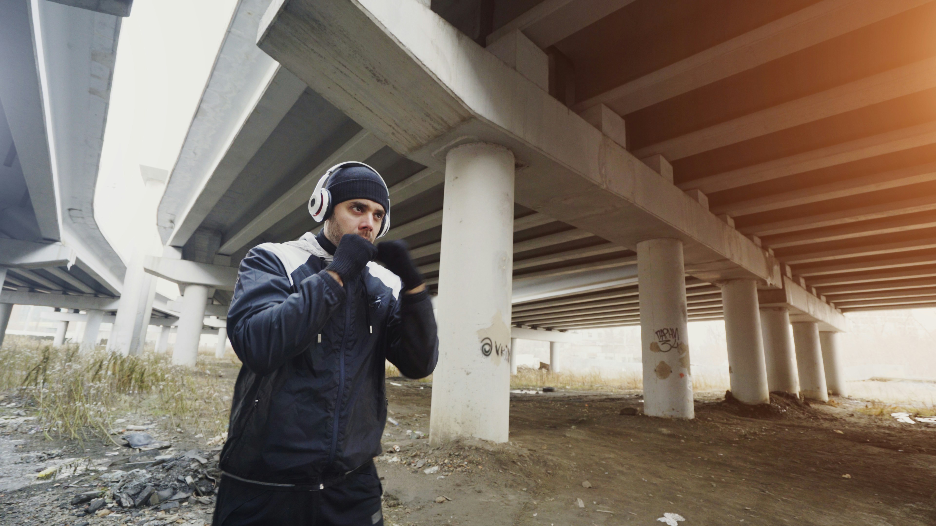 Man boxing under a concrete overpass wearing headphones