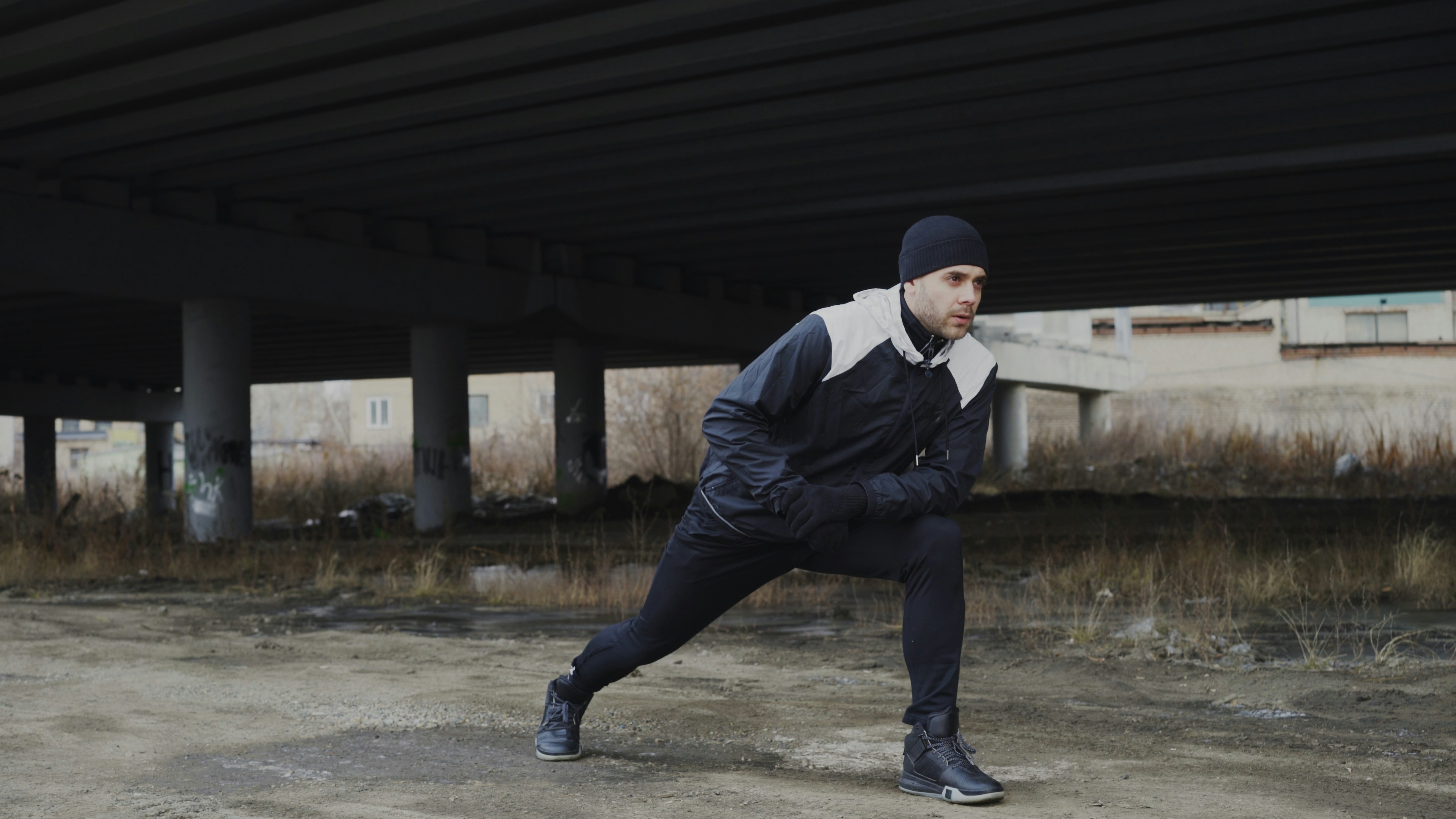 Attractive man runner doing stretching exercise for morning workout and jogging at urban location outdoors in winter season