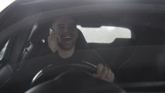 Man laughing while talking on phone in car
